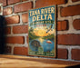 A vintage-style metal sign for the Tana River Delta in Kenya, featuring a scenic illustration of a hippopotamus, flamingo, and other wildlife in a tropical setting.