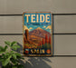 A vintage-style metal sign for Teide National Park in Spain, featuring a mountain landscape with a prominent peak and a blue sky with clouds.