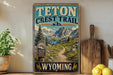 A vintage-style metal sign for the Teton Crest Trail in Wyoming, featuring a scenic mountain landscape with a trail leading through it.