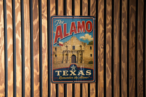 A vintage-style metal sign with the text "The Alamo" and "Texas Remember the Alamo!" displayed on a wooden wall.