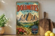 A vintage-style poster of the Dolomites mountain range in Italy, featuring a scenic landscape with mountains, a lake, and colorful flowers.