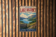 A vintage metal sign for the English Lake District, featuring a scenic landscape with mountains, a lake, and a stone wall.