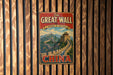 A vintage-style metal sign with the text "The Great Wall of China" and a depiction of the iconic wall, mounted on a wooden wall.