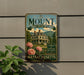 A vintage metal sign for "The Mount Edith Wharton's Home" in Massachusetts, featuring a large house surrounded by flowers and a mountain in the background.