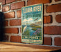 A vintage-style metal sign for the Tijuana River National Estuarine Research Reserve in California, featuring a scenic illustration of the river and surrounding landscape.