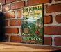A vintage-style metal sign for Tom Dorman State Nature Preserve in Kentucky, featuring a scenic landscape with a red cardinal perched on a branch.