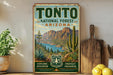 A vintage-style poster for Tonto National Forest in Arizona, featuring a desert landscape with mountains, cacti, and a lake.
