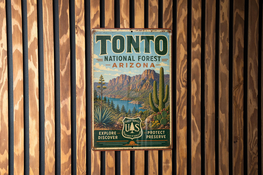 A vintage metal sign for Tonto National Forest in Arizona, featuring a scenic landscape with mountains, cacti, and a lake.