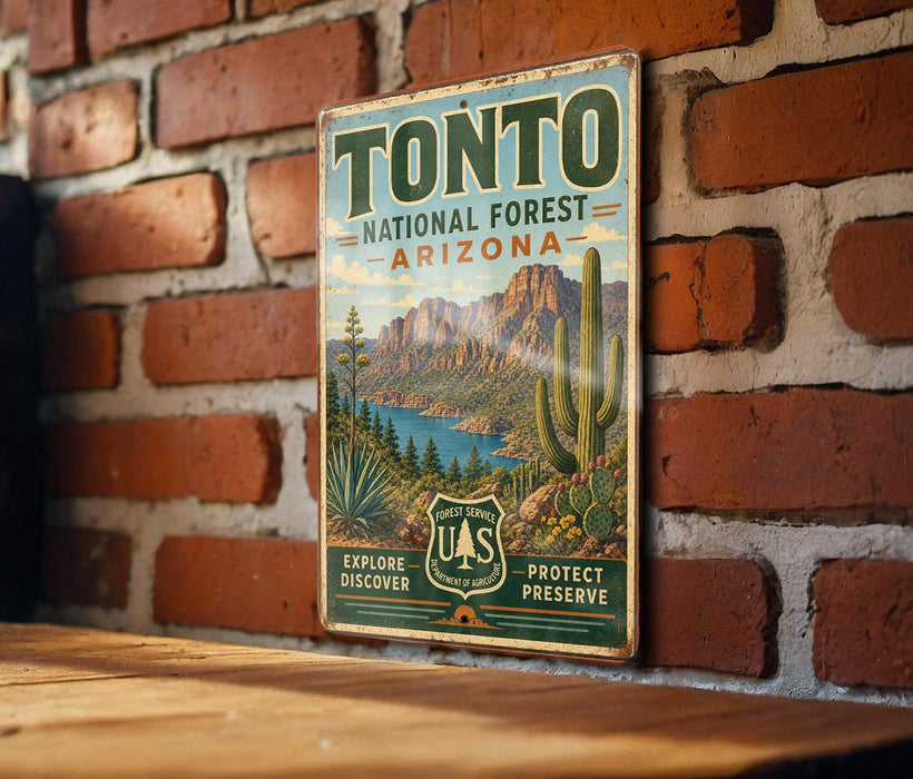 A vintage-style metal sign for Tonto National Forest in Arizona, featuring a desert landscape with mountains, cacti, and a body of water.