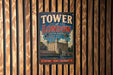 A vintage-style metal sign that reads "TOWER OF LONDON UNITED KINGDOM" is displayed on a wooden wall.