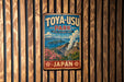 A vintage-style metal sign for Toya-USU Park, featuring a scenic landscape with mountains, flowers, and a volcano.