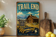 A vintage-style metal sign for Trail End State Historic Site in Wyoming, featuring a cabin in the background and a mountain range.