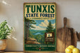 A vintage-style metal sign for the Tunxis State Forest in Connecticut, featuring a scenic landscape with pine trees and a river.