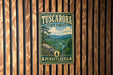 A vintage metal sign for Tuscarora State Forest in Pennsylvania, featuring a scenic landscape with a river and mountains.