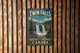 A vintage-style sign for Twin Falls, Territorial Park, Northwest Territories, Canada, featuring a waterfall and forest landscape.