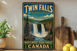 A vintage-style sign for Twin Falls, Territorial Park, Northwest Territories, Canada, featuring a waterfall and forest landscape.