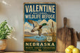 A vintage-style metal sign for Valentine National Wildlife Refuge in Nebraska, featuring a duck in flight over a scenic landscape.