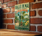 A vintage-style metal sign with a tropical landscape and palm trees is mounted on a brick wall.