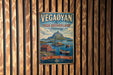 A vintage metal sign with a scenic illustration of a coastal landscape, featuring mountains, boats, and a wooden fence in the background.