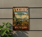 A vintage-style metal sign for Vickburg National Military Park, featuring a cannon and a river, is displayed on a wall.