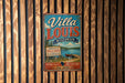 A vintage-style metal sign for Villa Louis Wisconsin, featuring a scenic landscape with a lake and pine trees.