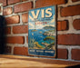 A vintage-style sign for VIS Archipelago Park in Croatia, featuring a scenic coastal landscape with a sailboat and palm trees.