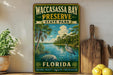 A vintage-style sign for Waccasass Bay Preserve, Florida, featuring a tropical landscape with palm trees, a bird, and a body of water.