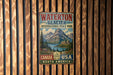 A vintage-style metal sign for Waterton Glacier International Peace Park, featuring a scenic mountain landscape with a lake and forest.
