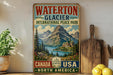 A vintage-style sign for Waterton Glacier International Peace Park, featuring a scenic mountain landscape with a lake and a castle in the distance.