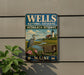 A vintage metal sign for the Wells National Estuarine Research Reserve in Maine, featuring a seagull, flowers, and a lighthouse.