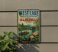 A vintage-style sign for West Lake, a cultural landscape in Hangzhou, China, featuring a scenic image of a traditional Chinese boat on the water.