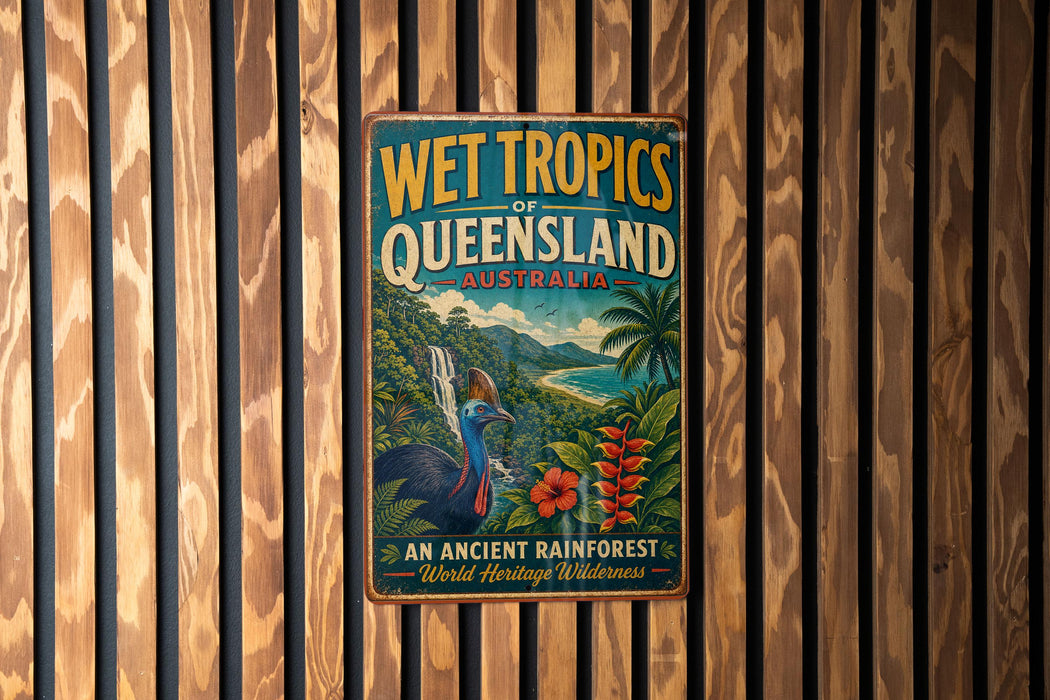 A vintage-style metal sign advertising the Wet Tropics of Queensland, Australia, featuring a colorful illustration of a tropical landscape with a bird and flowers.