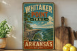 A vintage-style sign for Whitaker Point Trail in Arkansas, featuring a scenic mountain landscape with a river and pine trees.
