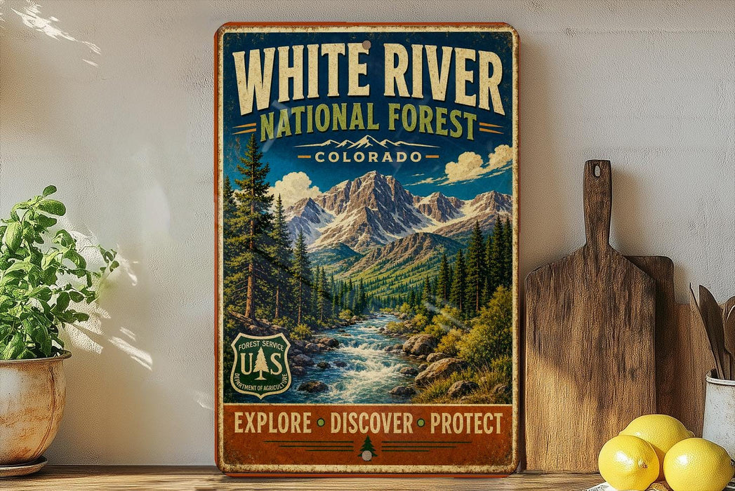 A vintage-style metal sign for the White River National Forest in Colorado, featuring a scenic mountain landscape with a river flowing through it.