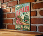 A vintage-style metal sign for the Wild Azalea Trail in Louisiana, featuring a scenic landscape with a road and flowers.