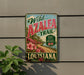 A vintage-style metal sign advertising the Wild Azalea Trail in Louisiana, featuring a scenic landscape with a road and flowers.