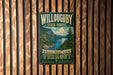 A vintage metal sign for Willoughby State Forest in Vermont, featuring a scenic landscape with mountains, a lake, and pine trees.