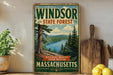 A vintage-style metal sign for the Windsor State Forest in Massachusetts, featuring a scenic landscape with pine trees, a river, and mountains.