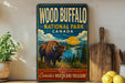 A vintage-style sign for Wood Buffalo National Park in Canada, featuring an illustration of a bison in a grassy field with mountains in the background.