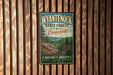 A vintage metal sign for Wyantenock State Forest in Connecticut, featuring a scenic image of the forest and mountains.