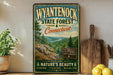 A vintage-style metal sign for Wyantenock State Forest in Connecticut, featuring a scenic landscape with pine trees, a lake, and mountains.