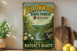 A vintage-style sign for the Yellowwood State Forest in Indiana, featuring a scenic landscape with a river and mountains.