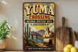 A vintage-style sign for Yuma Crossing, a National Heritage Area in Arizona, featuring a desert landscape with a bridge, cacti, and a wagon.