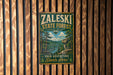 A vintage metal sign for the Zaleski State Forest in Ohio, featuring a scenic landscape with pine trees and a river.