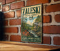 A vintage-style metal sign for the Zaleski State Forest in Ohio, featuring a scenic landscape with a waterfall and autumn foliage.