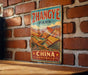 A vintage-style metal sign with the text "Zhangye Park - China" displayed on a brick wall.