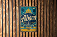 A vintage metal sign with the word "Abaco" displayed prominently in the center, featuring a sun and palm trees, is mounted on a wooden wall.