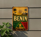 a vintage-style sign with the word "BENIN" prominently displayed, surrounded by various tropical and cultural elements such as palm trees, a sun, and a boat.