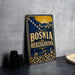 A vintage-style metal sign with the text "BOSNIA AND HERZEGOVINA" displayed prominently, featuring an illustration of a cityscape and a sun.
