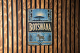 A vintage-style metal sign with the word "Botswana" prominently displayed, featuring a zebra and other wildlife elements.
